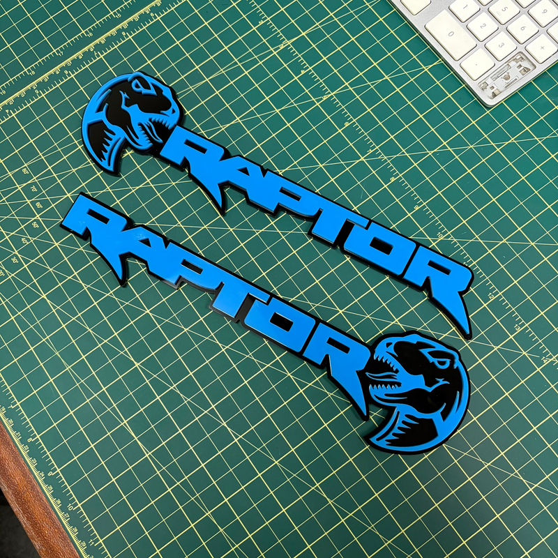 Load image into Gallery viewer, Nitrous blue Ford Raptor Emblems pair with dino head on green mat