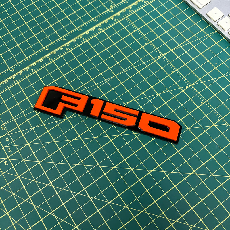 Load image into Gallery viewer, F150 emblem in orange on a green mat
